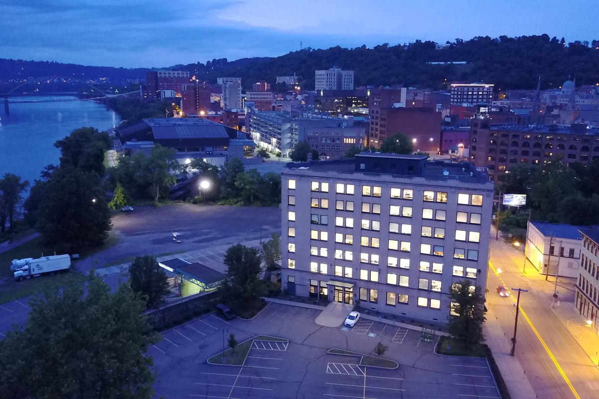 Illuminated multi-story commercial building managed by Harvey Goodman Property Management, overlooking the Ohio River at dusk